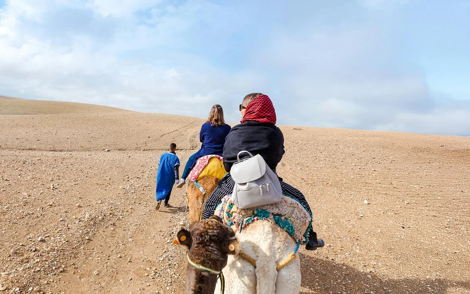 Camel riders following a guide across a dry rocky plateau