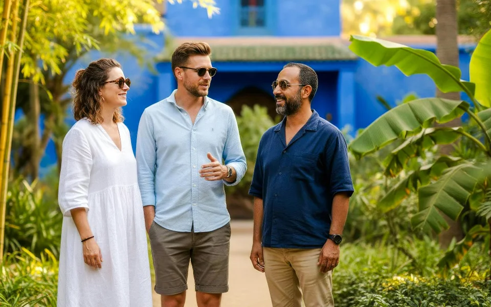Visitors talking beside lush planting and blue architecture at Jardin Majorelle